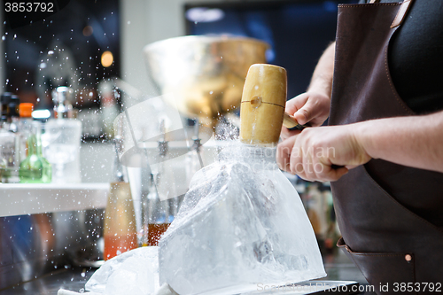 Image of Bartender mannually crushed ice with wooden hammer and metal knife.