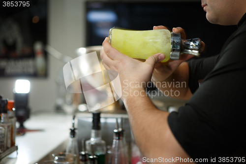 Image of Bartender at work preparing cocktails. Shaking cocktail shaker. 