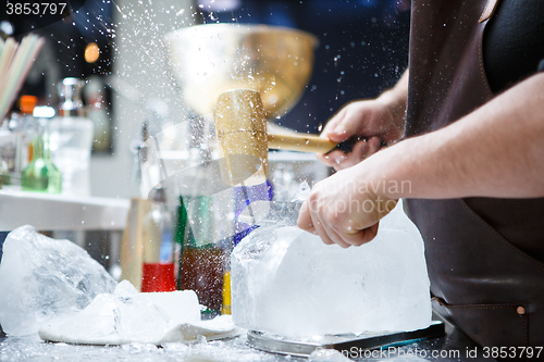 Image of Bartender mannually crushed ice with wooden hammer and metal knife.