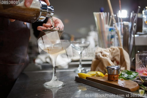 Image of Bartender coocks cocktail behind a bar counter