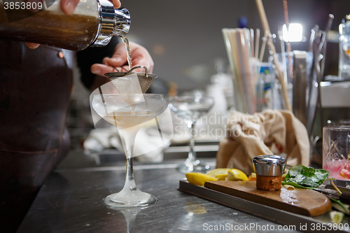 Image of Bartender coocks cocktail behind a bar counter