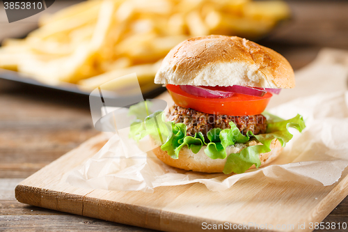 Image of Homemade burger with french fries on wooden table