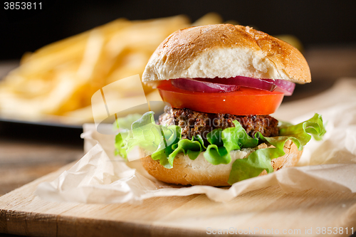 Image of Homemade burger with french fries on wooden table