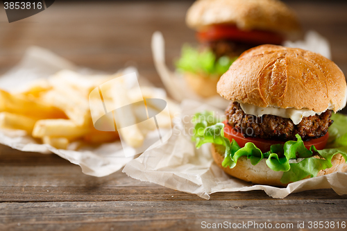 Image of Homemade tasty burger and french fries on wooden table