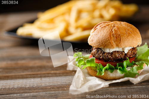 Image of Homemade burger with french fries on wooden table