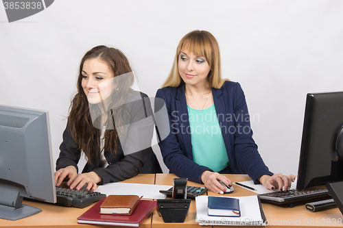 Image of Office worker on the sly looks at the monitor unsuspecting colleagues