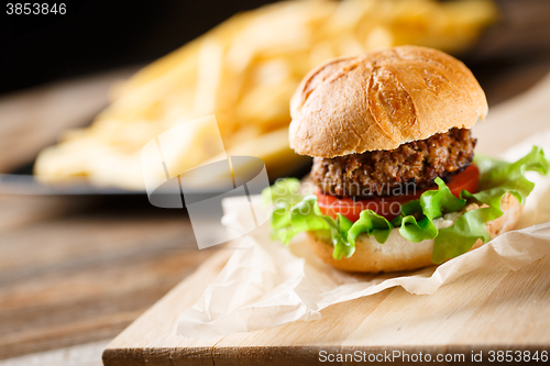 Image of Homemade burger with french fries on wooden table