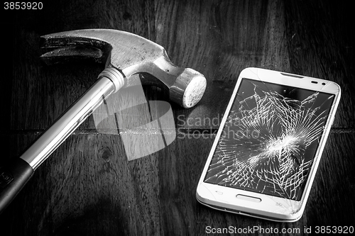 Image of Broken smartphone and a hammer