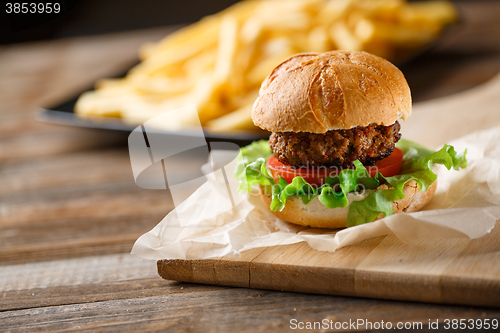 Image of Homemade burger with french fries on wooden table