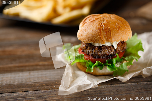 Image of Homemade burger with french fries on wooden table