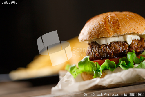 Image of Homemade burger with french fries on wooden table