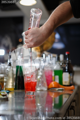 Image of Bartender coocks cocktail behind a bar counter