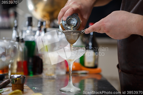 Image of Bartender coocks cocktail behind a bar counter