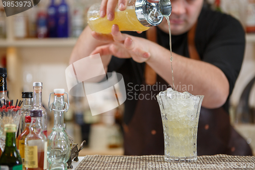 Image of Bartender pouring cocktail into glass at the bar