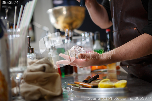 Image of Bartender pours alcoholic drink into small glasses with flames