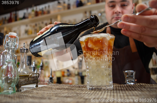 Image of Bartender pouring cocktail into glass at the bar