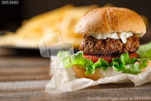 Image of Homemade burger with french fries on wooden table