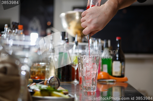 Image of Bartender coocks cocktail behind a bar counter