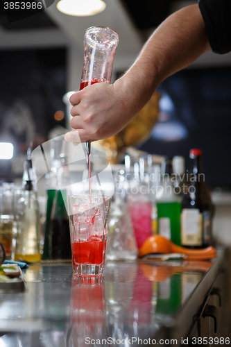 Image of Bartender coocks cocktail behind a bar counter