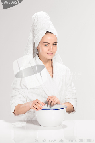 Image of Woman cleaning face in bathroom