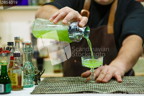 Image of barman pouring a pink cocktail drink 