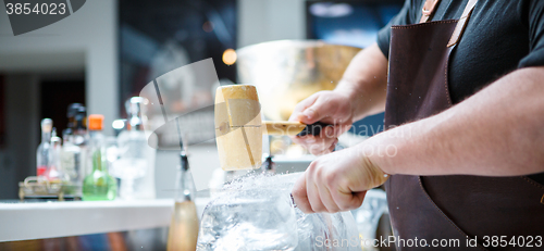 Image of Bartender mannually crushed ice with wooden hammer and metal knife.