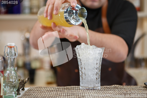 Image of Bartender pouring cocktail into glass at the bar