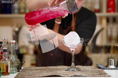 Image of barman pouring a pink cocktail drink 