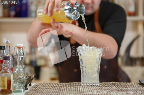 Image of Bartender pouring cocktail into glass at the bar