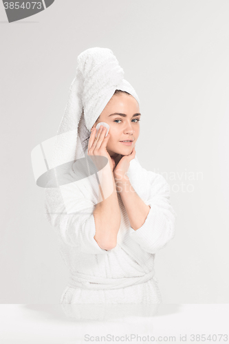 Image of Woman cleaning face in bathroom