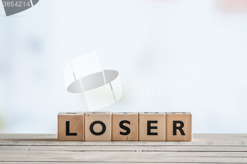 Image of Loser sign on a wooden desk