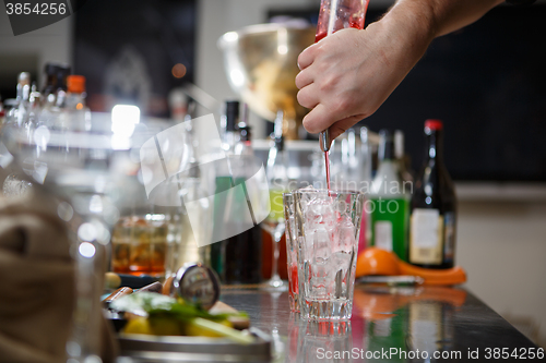 Image of Bartender coocks cocktail behind a bar counter