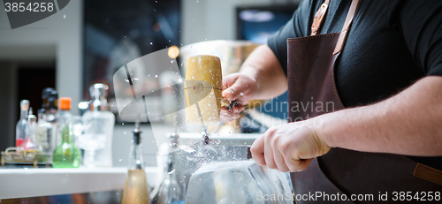 Image of Bartender breaks ice with wooden hammer