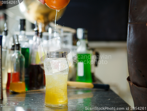 Image of Bartender is straining cocktail in a glass