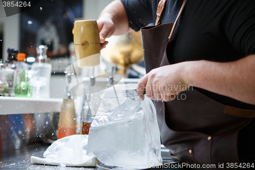 Image of Bartender mannually crushed ice with wooden hammer and metal knife.