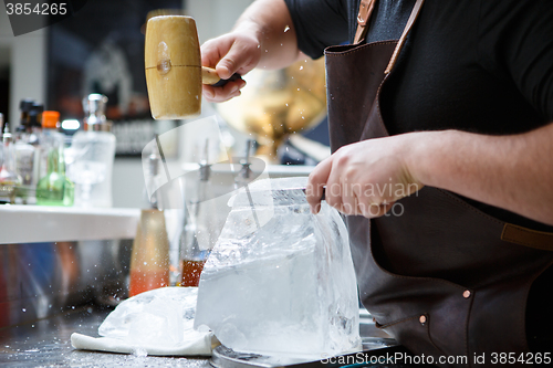 Image of Bartender mannually crushed ice with wooden hammer and metal knife.