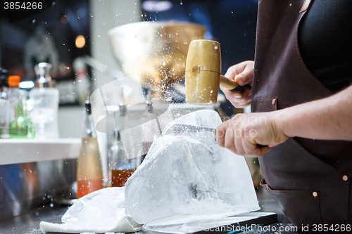 Image of Bartender mannually crushed ice with wooden hammer and metal knife.