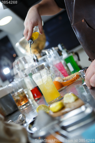 Image of Bartender is straining cocktail in a glass