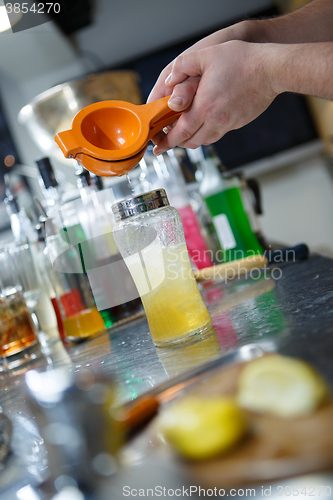 Image of Bartender is straining cocktail in a glass