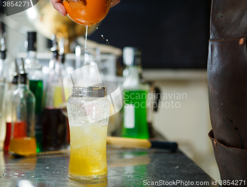 Image of Bartender is straining cocktail in a glass