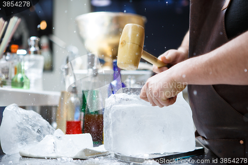 Image of Bartender mannually crushed ice with wooden hammer and metal knife.