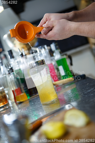 Image of Bartender is straining cocktail in a glass