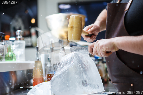 Image of Bartender mannually crushed ice with wooden hammer and metal knife.