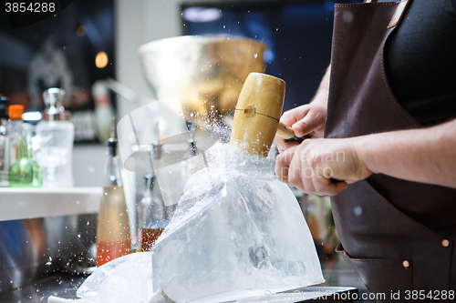 Image of Bartender mannually crushed ice with wooden hammer and metal knife.