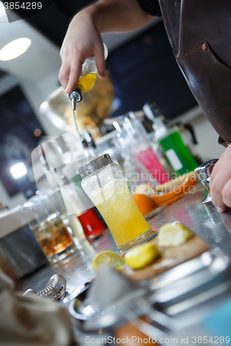 Image of Bartender is straining cocktail in a glass