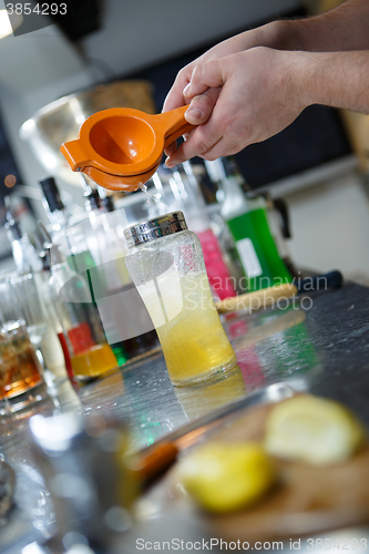 Image of Bartender is straining cocktail in a glass