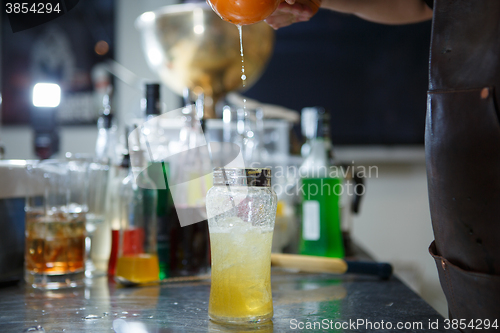 Image of Bartender is straining cocktail in a glass