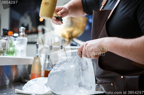 Image of Bartender mannually crushed ice with wooden hammer and metal knife.