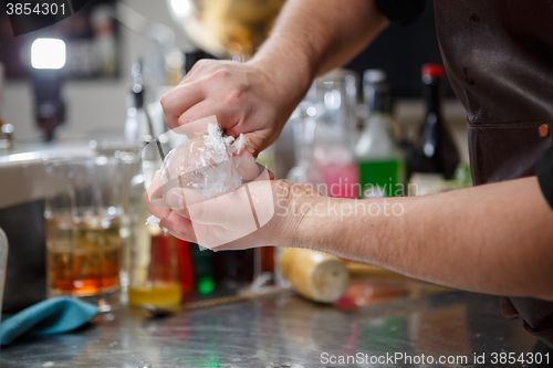 Image of Bartender pours alcoholic drink into small glasses with flames