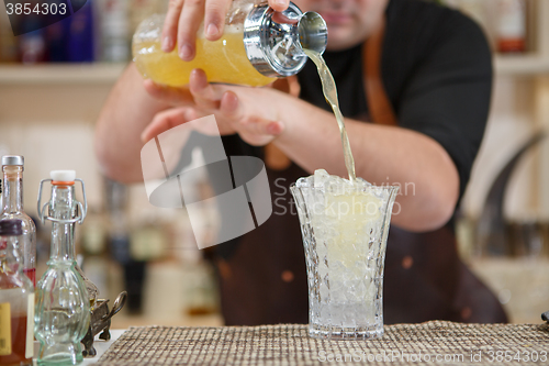 Image of Bartender pouring cocktail into glass at the bar